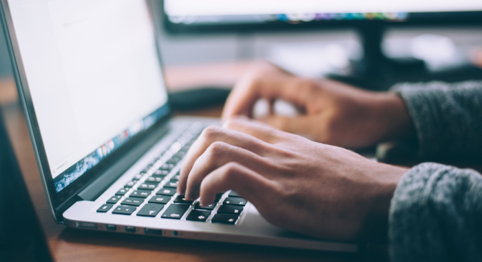 Person typing on laptop keyboard writing a blog