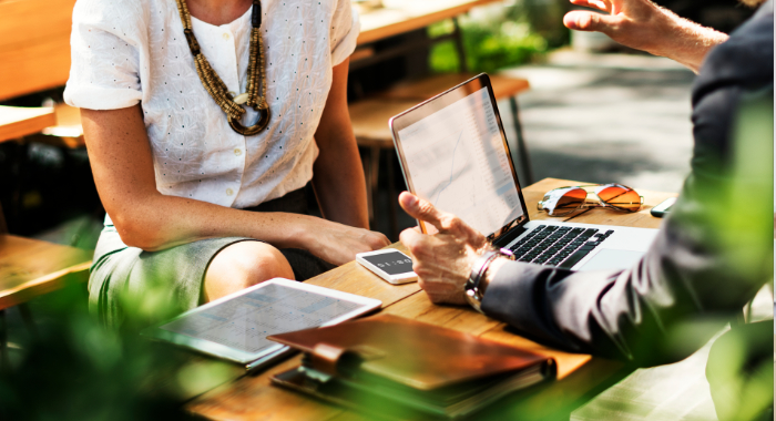 Man in suit with open laptop is sitting down talking to woman